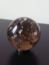 Load image into Gallery viewer, Round crystal-like object on a black surface with a white background
